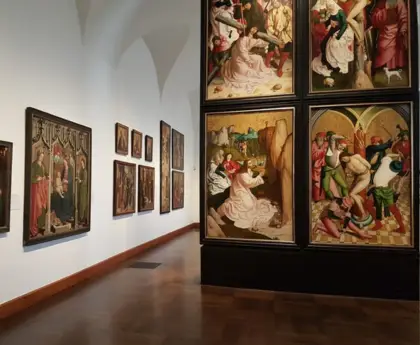 Belvedere art gallery room with wooden floors and walls displaying classical and religious paintings.