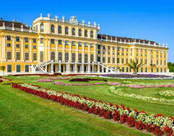 Schönbrunn Palace with colorful flower gardens in the foreground.