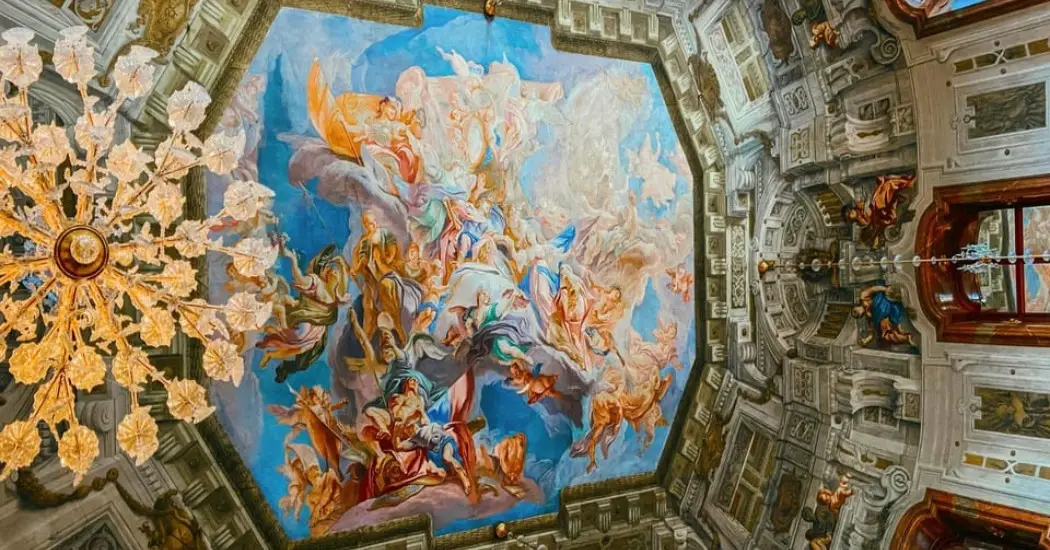 Colorful Baroque ceiling fresco with angels and clouds inside Belvedere Palace.