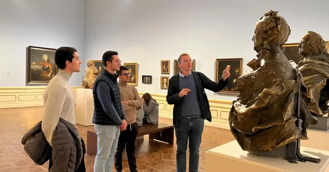 Visitors on a guided tour at Belvedere Palace, viewing classic sculptures and paintings in the museum gallery.