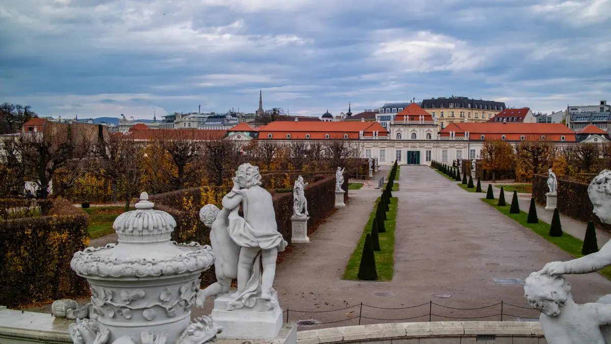 A long pathway lined with stone sculptures leading to Lower Belvedere Palace.
